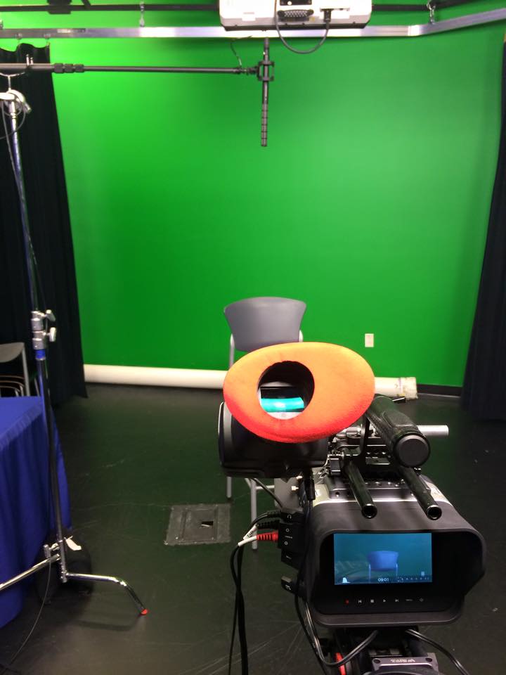 A camera focuses on a green scsreen