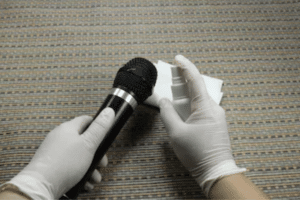 Sanitizing a microphone with latex gloves.
